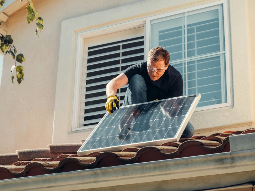 Ein Mann montiert eine Solaranlage auf einem Vordach.