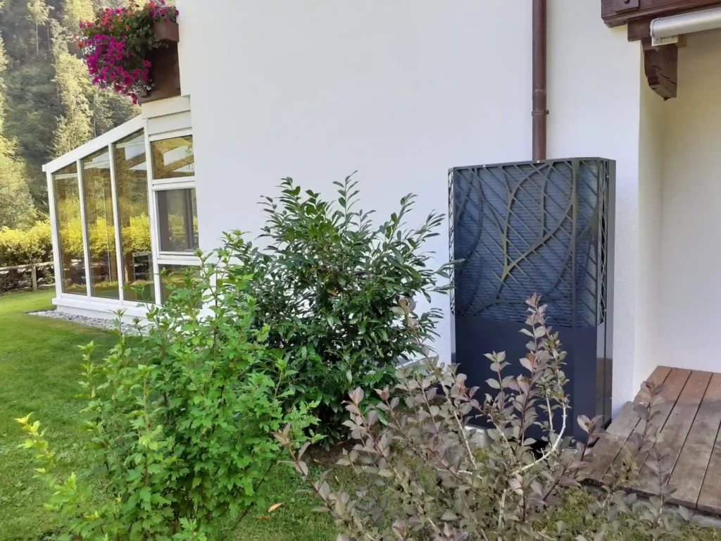 Hausgarten mit moderner Wärmepumpe, umgeben von Pflanzen und Blumen, bietet nachhaltige Heizlösung in der Natur.